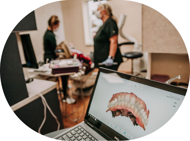 Computer screen showing digital model of teeth with dental patient being treated in background