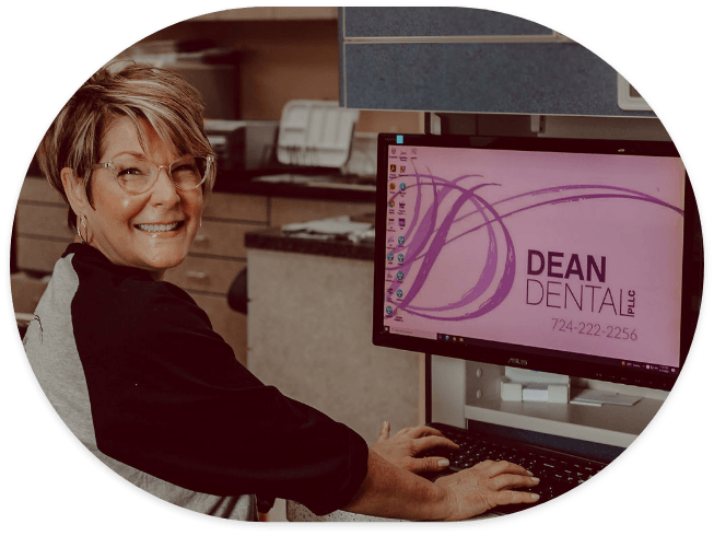Dean Dental team member smiling while sitting at computer