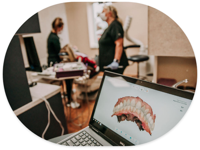 Digital model of teeth on computer monitor with dental patient being treated in background