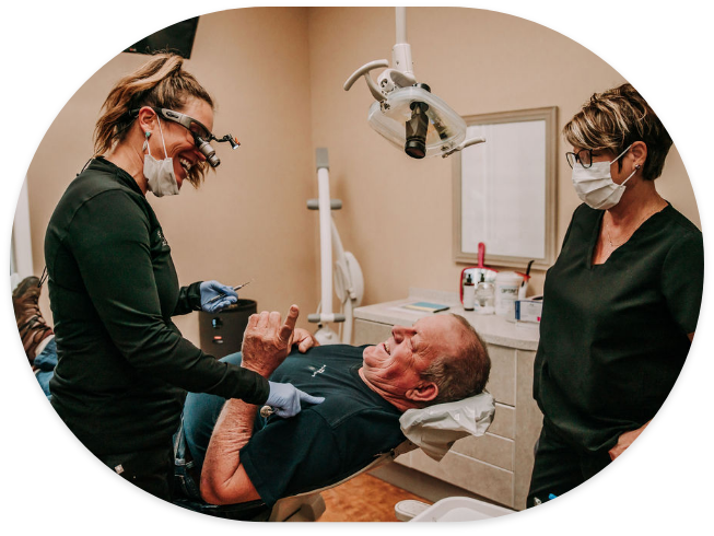 Dentist and assistant laughing with dental patient