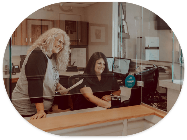 Two smiling team members at front desk