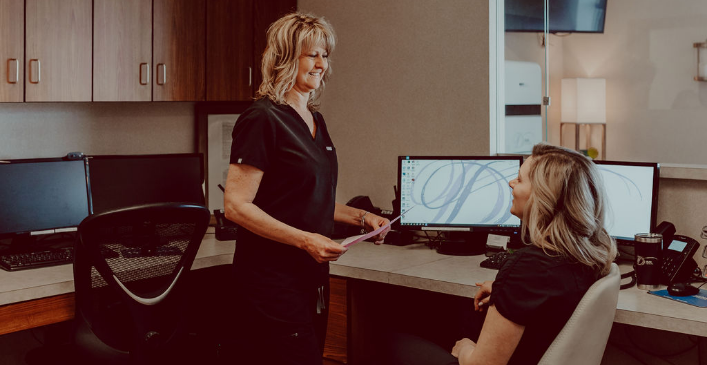 Two dental team members talking while at front desk