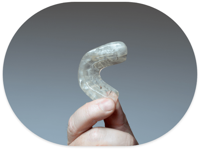 Hand holding a white oral appliance for bruxism treatment