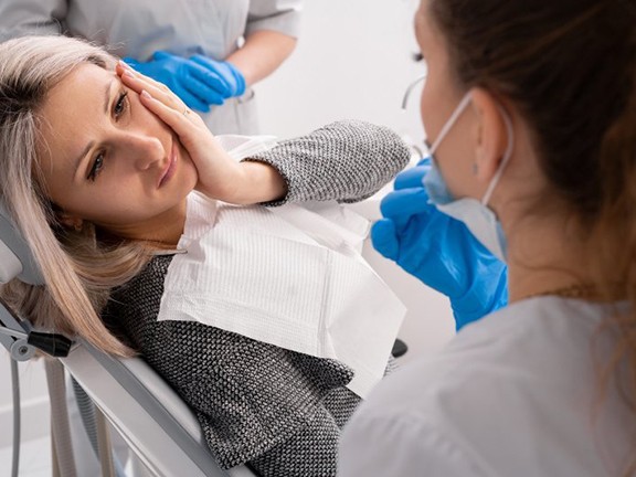 Lady with oral pain looks to dentist