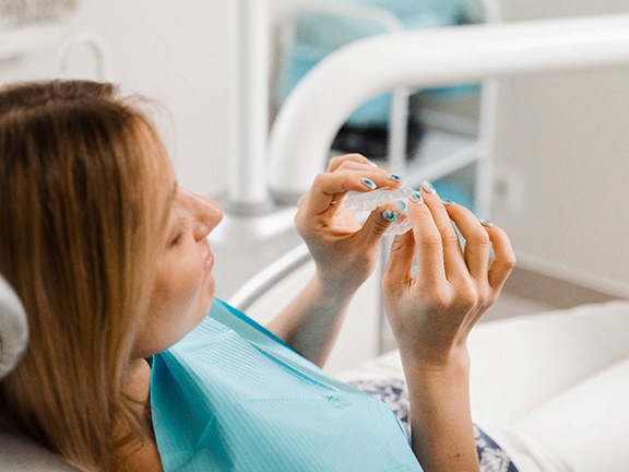 Patient holding clear aligner in treatment room