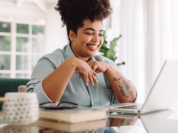 Woman smiling while working on laptop at home