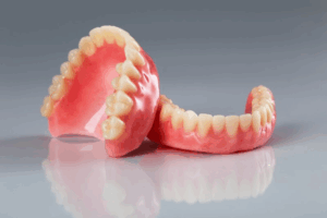 Two dentures resting against each other on a clear surface